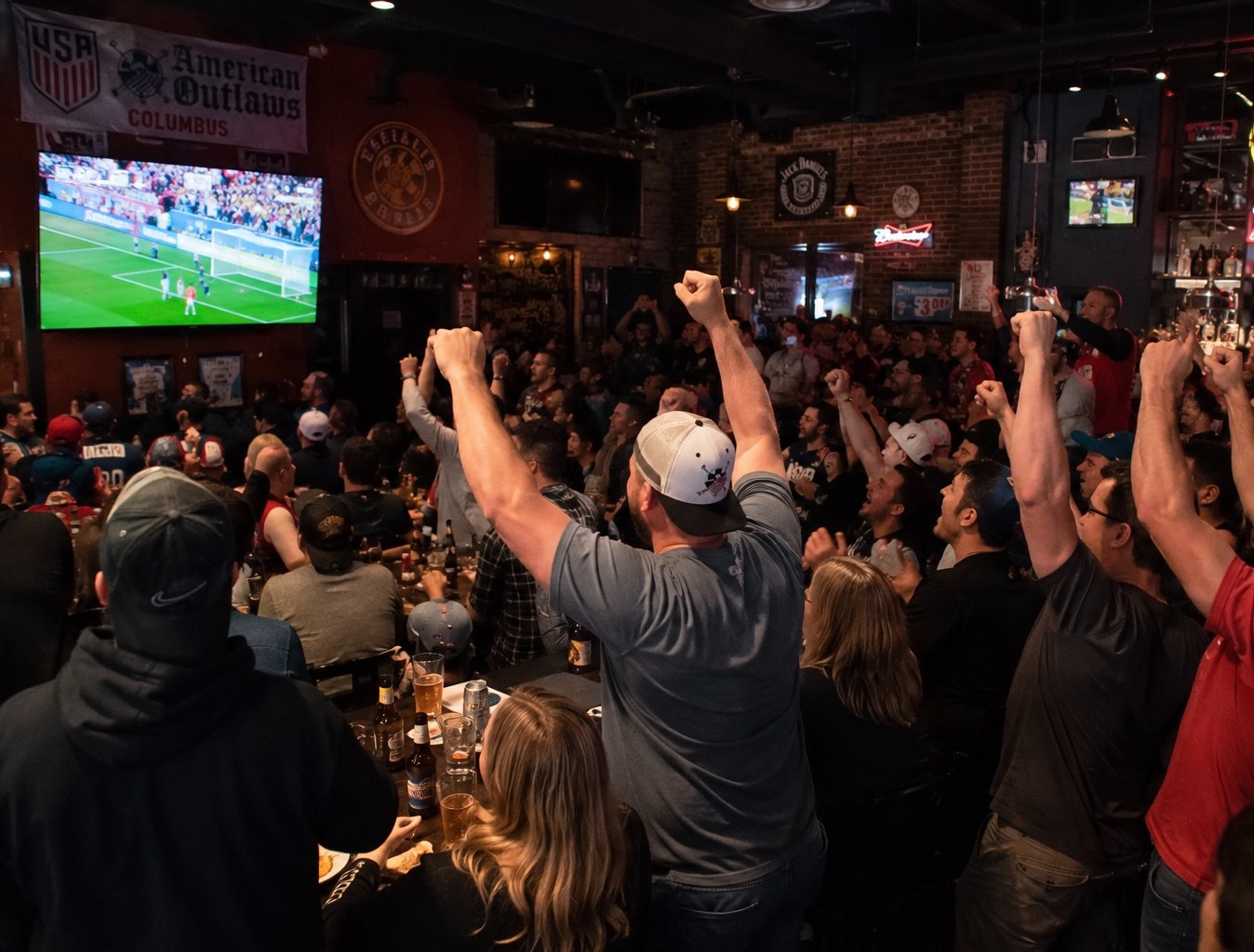 Fans cheering at the bar during a game